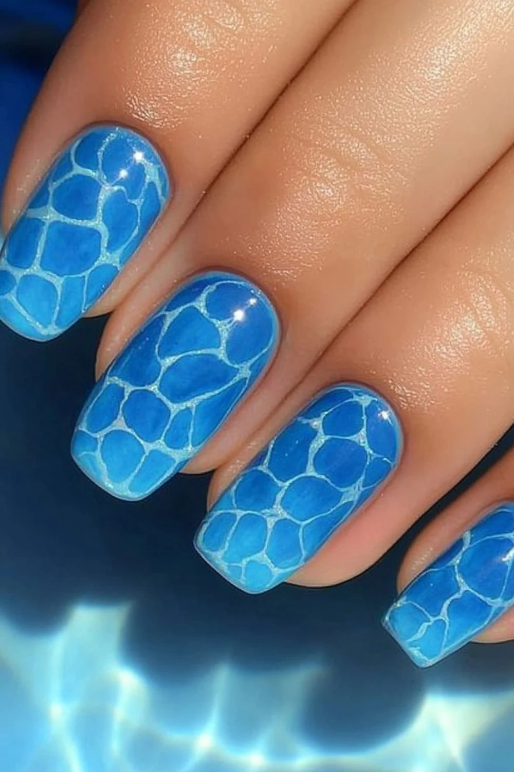 A set of square-shaped nails featuring a pool water effect design. The nails have a vibrant blue base with intricate white lines mimicking sunlight reflections on water, creating a realistic aquatic look.
