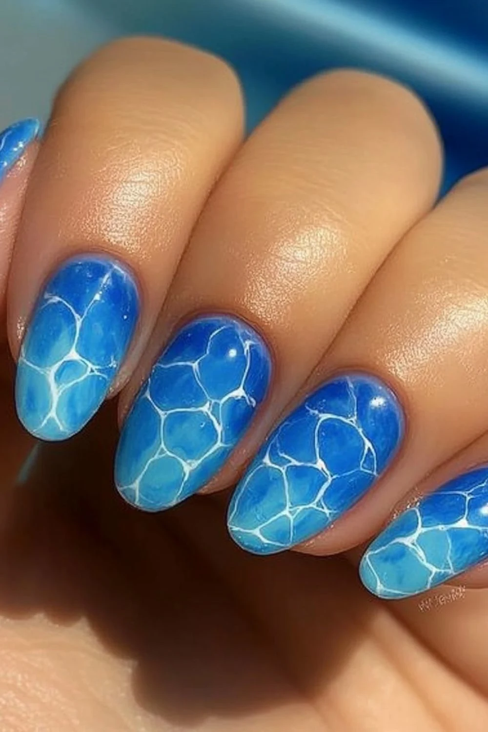 Blue ocean reflection nail design with a glossy finish and white ripple effect.