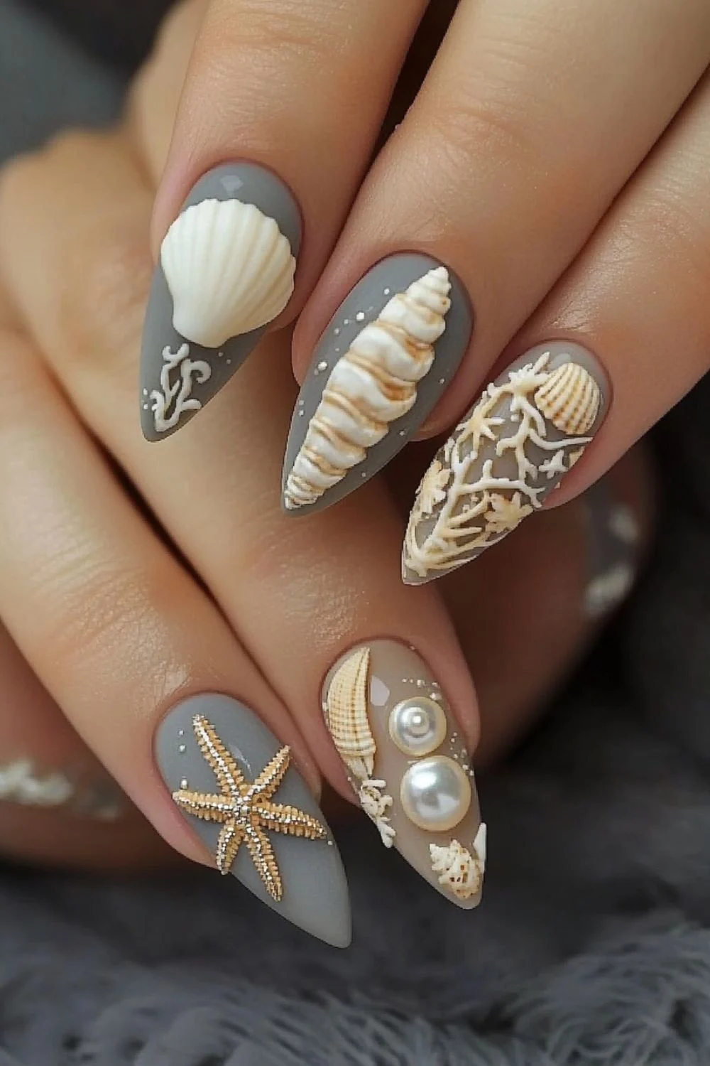 Matte gray nails with 3D seashell, starfish, and pearl decorations for an elegant beach-inspired manicure.