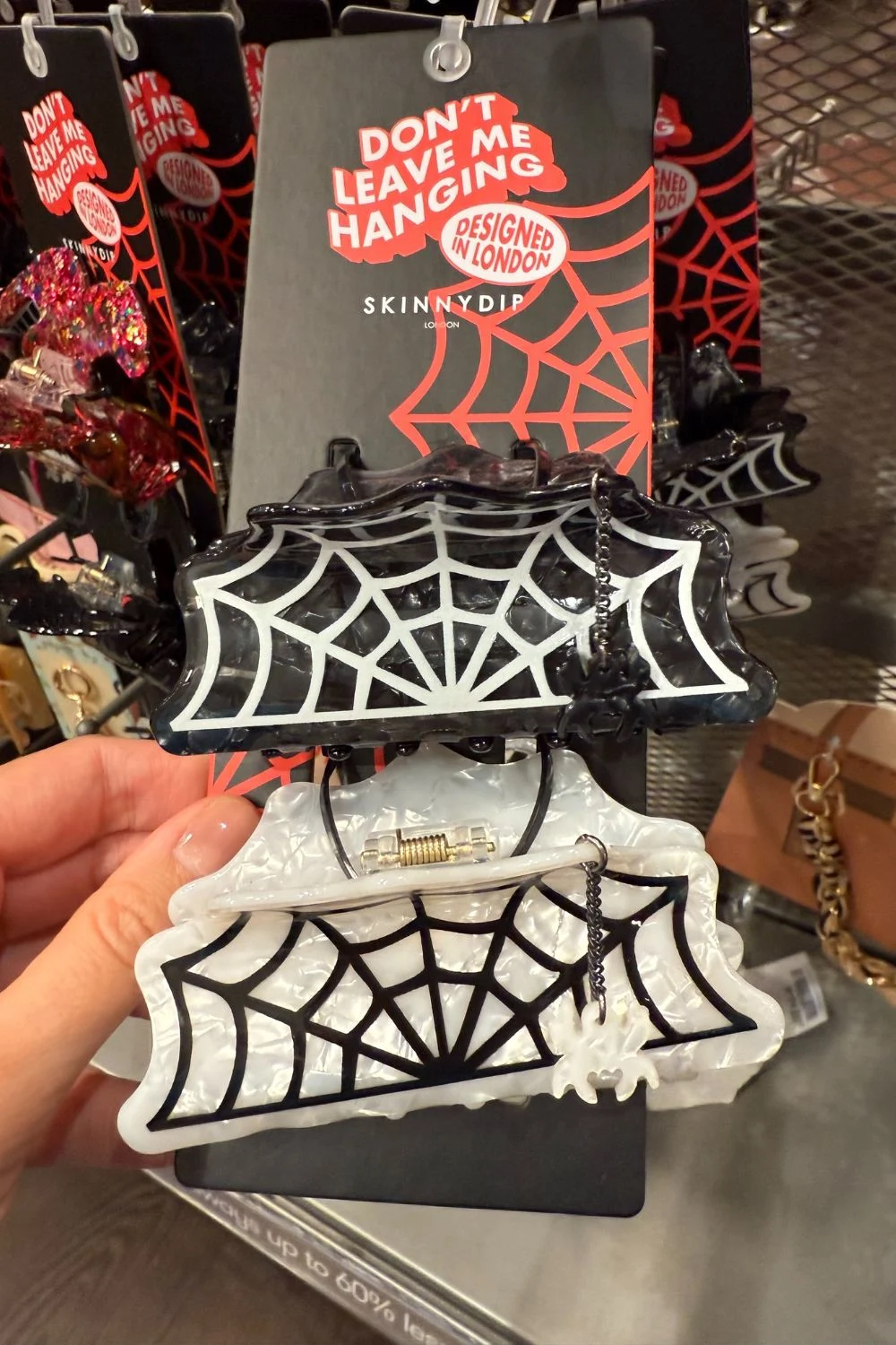 Black and white spiderweb claw clips with dangling spider charm.