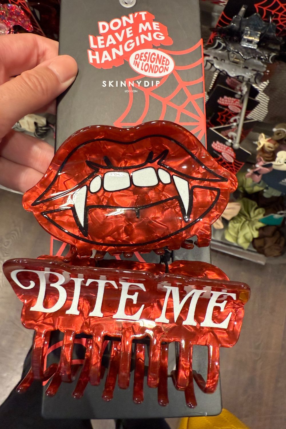 Red vampire lips hair clip with fangs and "BITE ME" text.