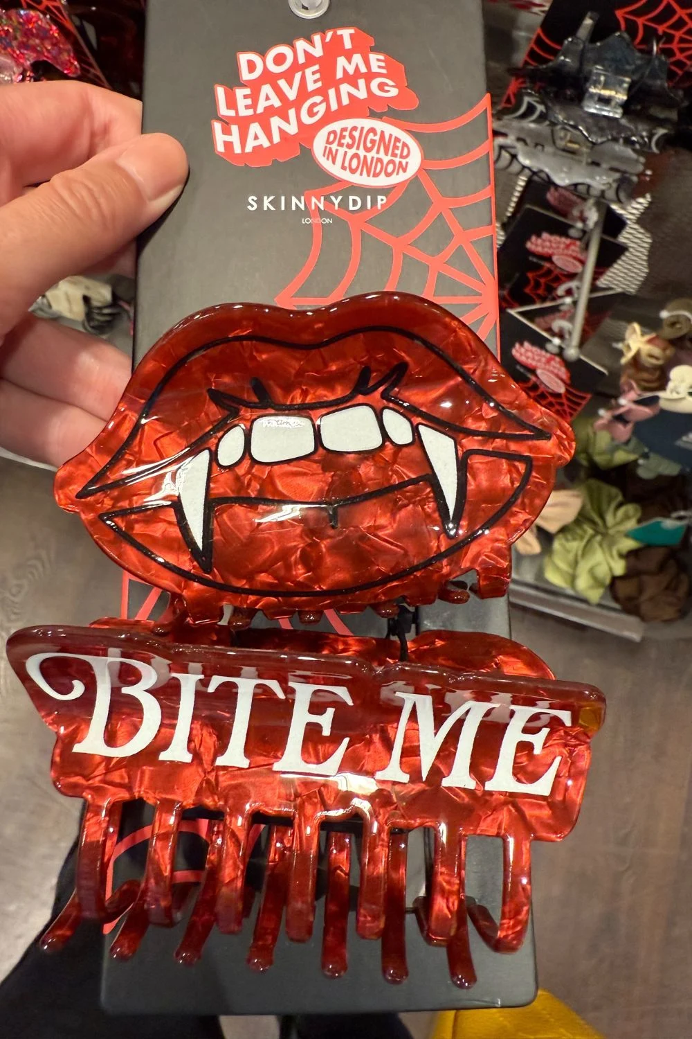 Red vampire lips hair clip with fangs and "BITE ME" text.