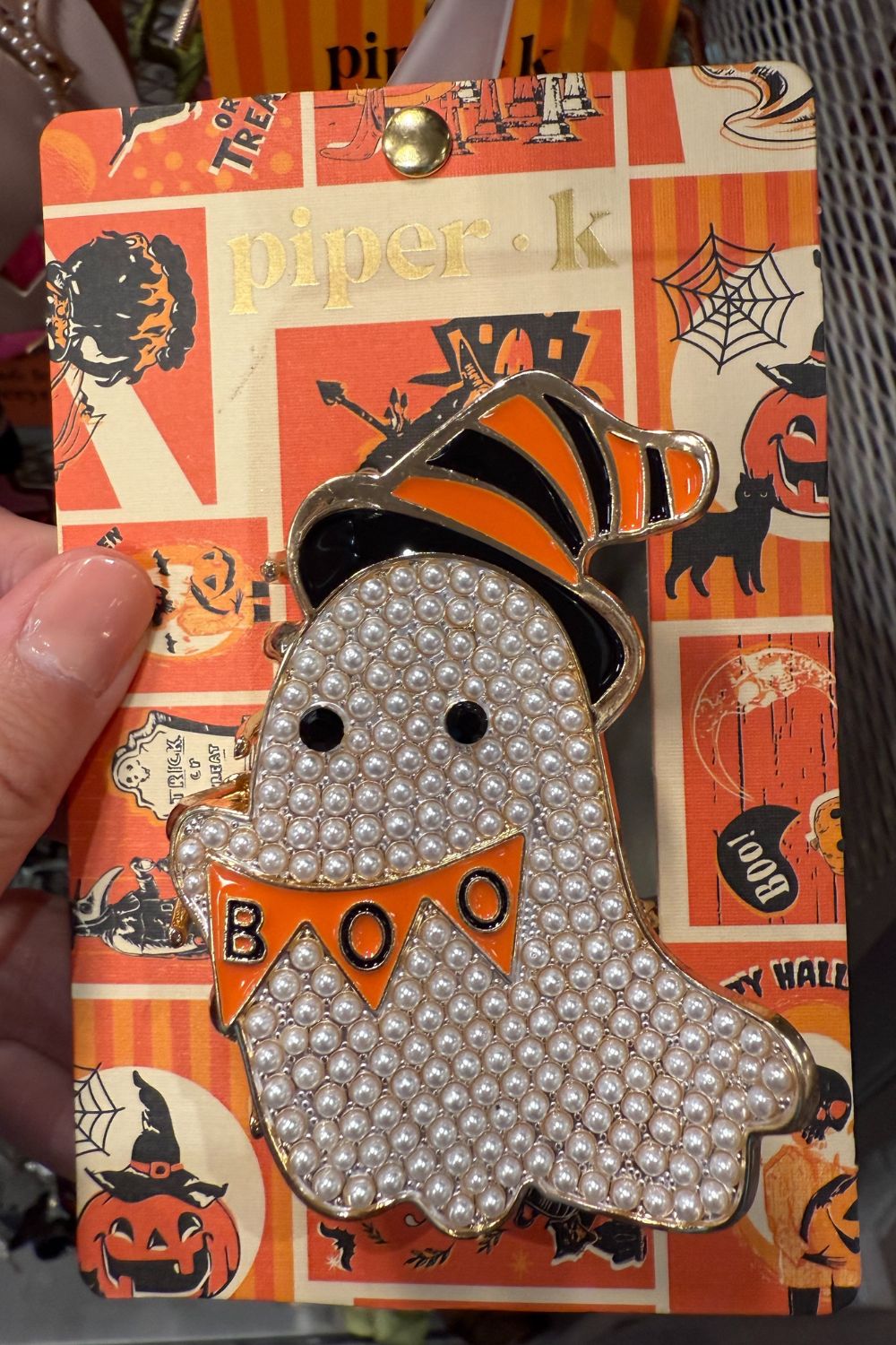 Pearl-encrusted ghost hair clip with orange "BOO" banner and striped witch hat.