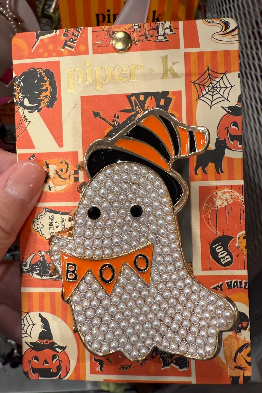 Pearl-encrusted ghost hair clip with orange "BOO" banner and striped witch hat.