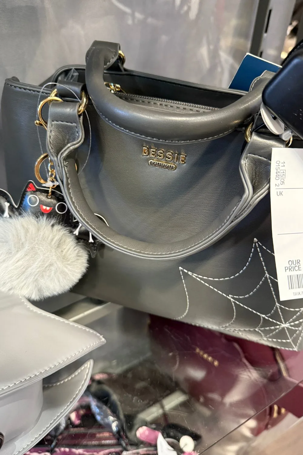Grey Bessie London handbag with stitched spiderweb detail and a fluffy bat keychain.