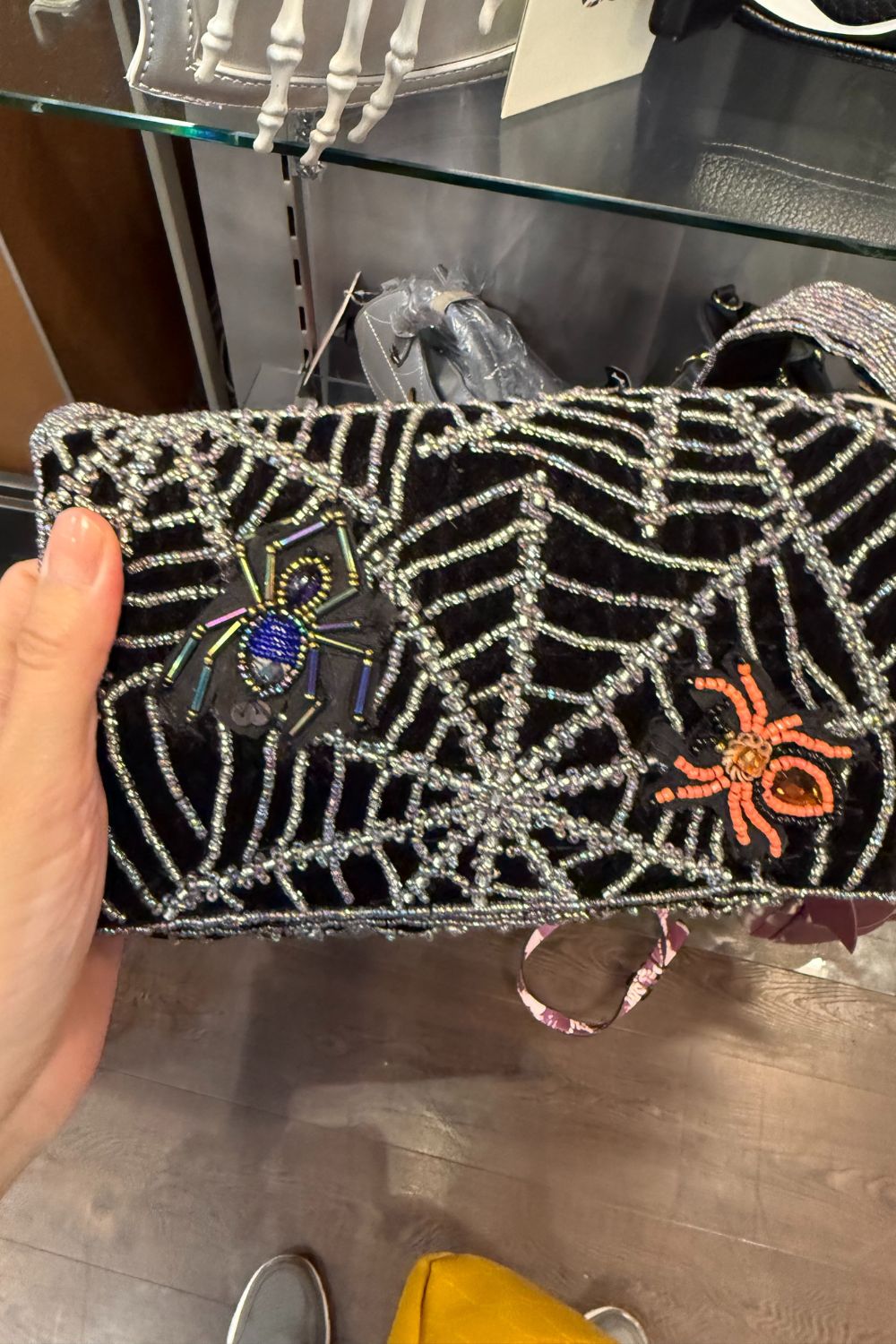 Black beaded clutch bag with silver spiderwebs and two colorful beaded spiders.