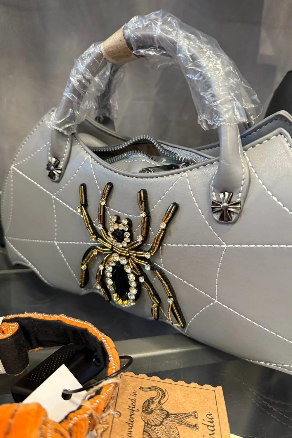 Silver handbag with spiderweb stitching and a gold and rhinestone jeweled spider.
