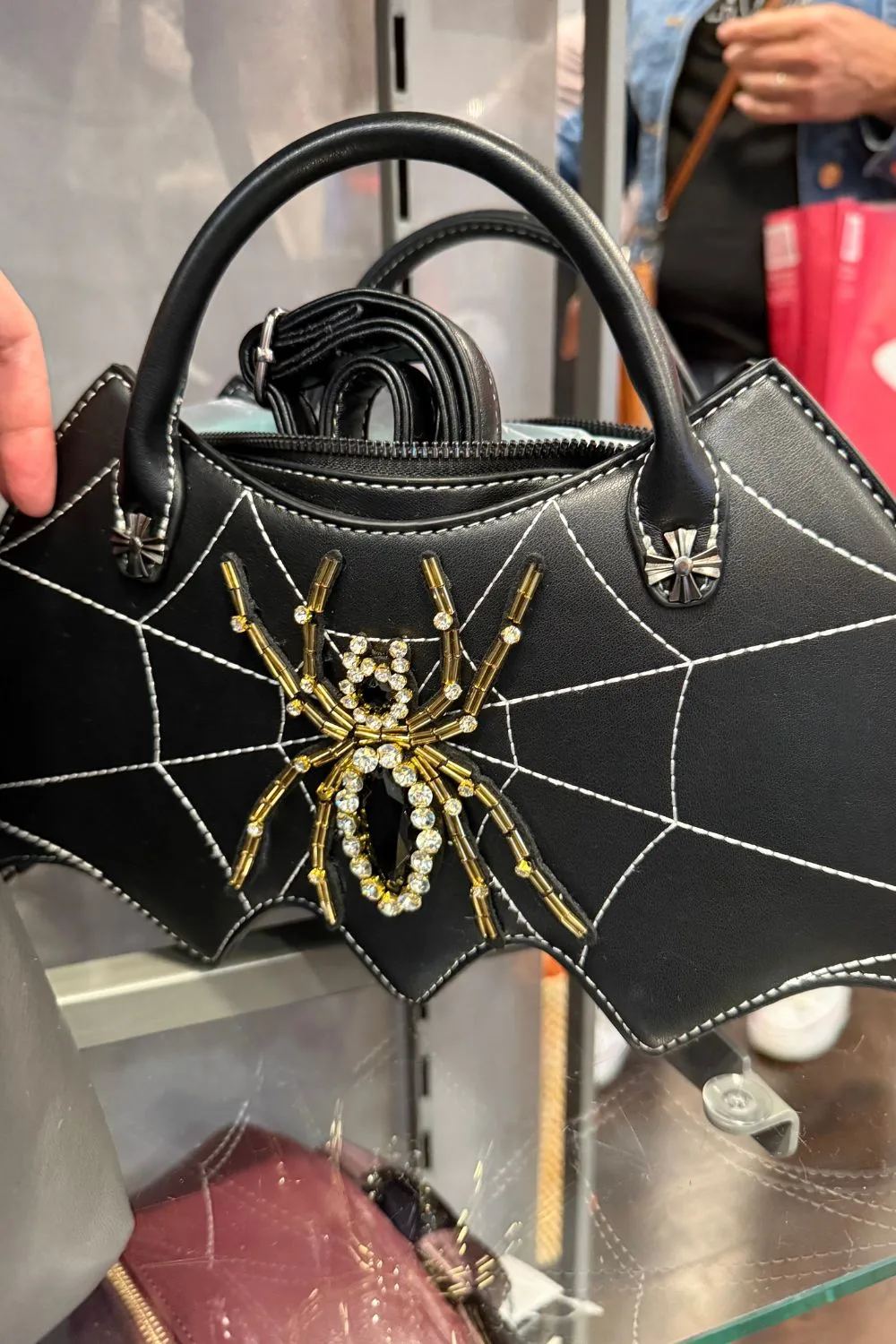 Black handbag with white spiderweb stitching and a rhinestone jeweled spider.