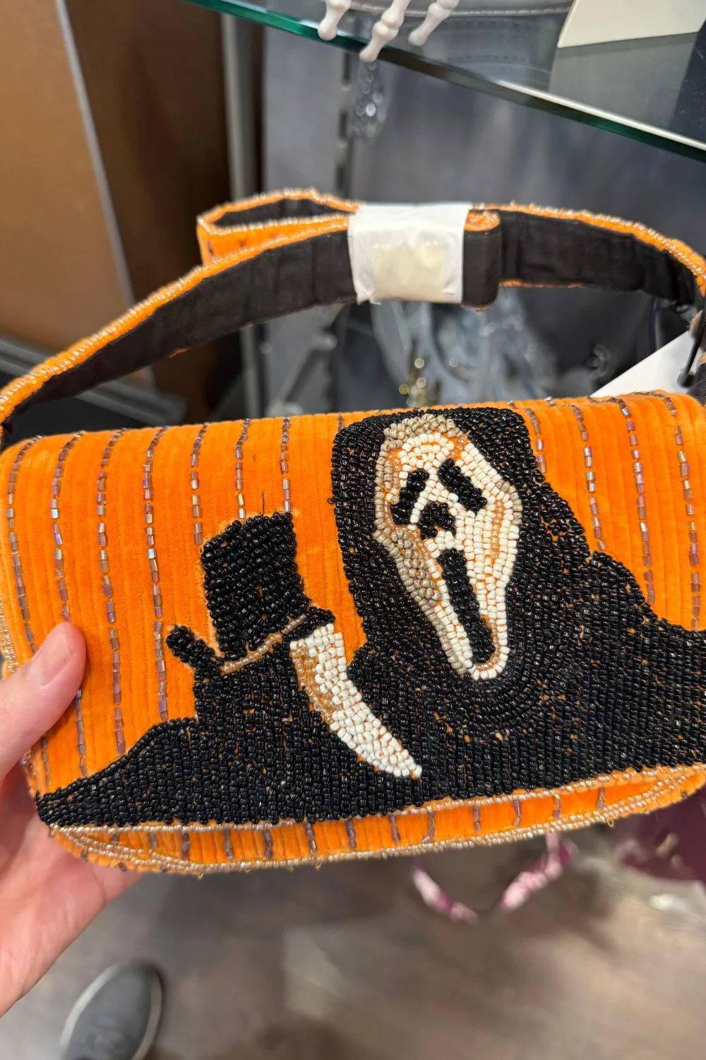 Orange beaded handbag with a black and white Ghostface mask design holding a knife.