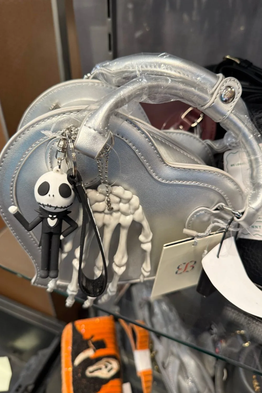 Silver handbag with a skeleton hand detail and a Jack Skellington keychain charm.