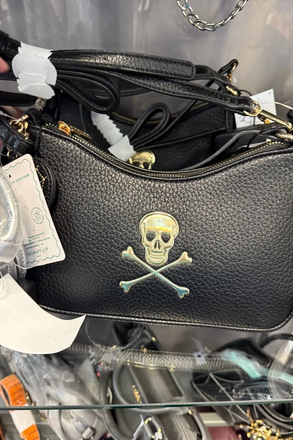 Black faux leather handbag with a metallic skull and crossbones design on the front.