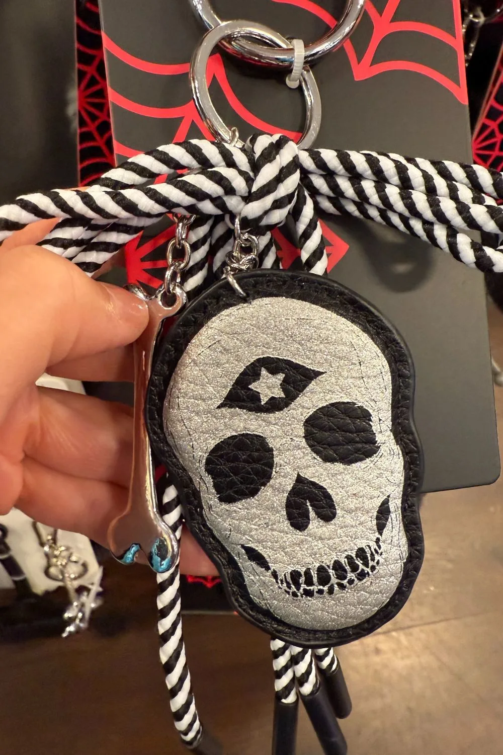 Silver skull Halloween bag charm with striped cord and bone charm.
