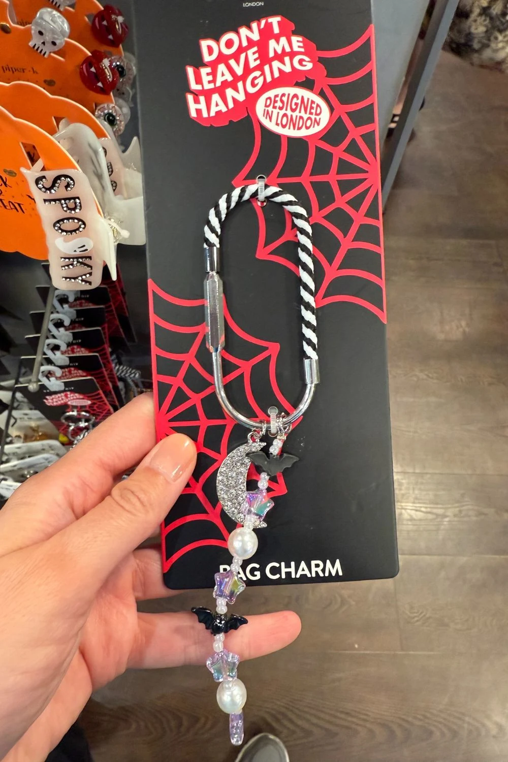 Halloween bag charm with moon, bats, and pearls hanging on a striped cord.